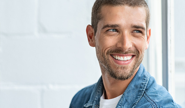 smiling man wearing denim jacket with light background showcasing positive energy and happiness perfect for lifestyle content about engaging 2 different perspectives