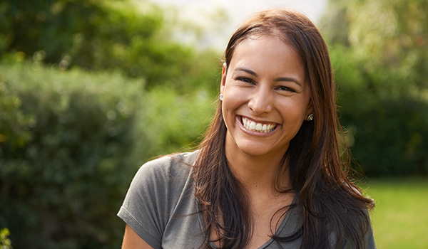 smiling woman with long hair outdoors in a green garden enjoying happiness with six different expressions