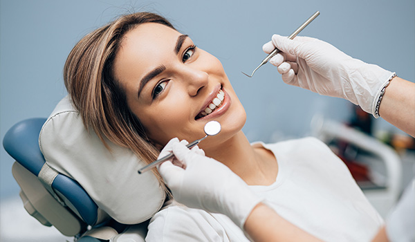 smiling woman in dental chair with tools in hands dental checkup bright smile dental health 4 tips for care