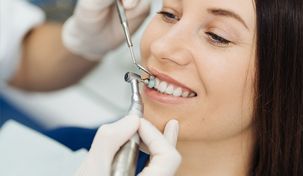 woman receiving dental cleaning smiling with bright teeth dental tools expert care 10 dental tips