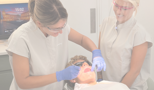 a dental hygienist and dental nurse with a patient having their oral health assessed