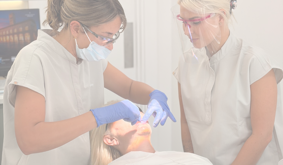 a dental hygienist and dental nurse using disclosing liquid to show where biolfim is hiding in the mouth